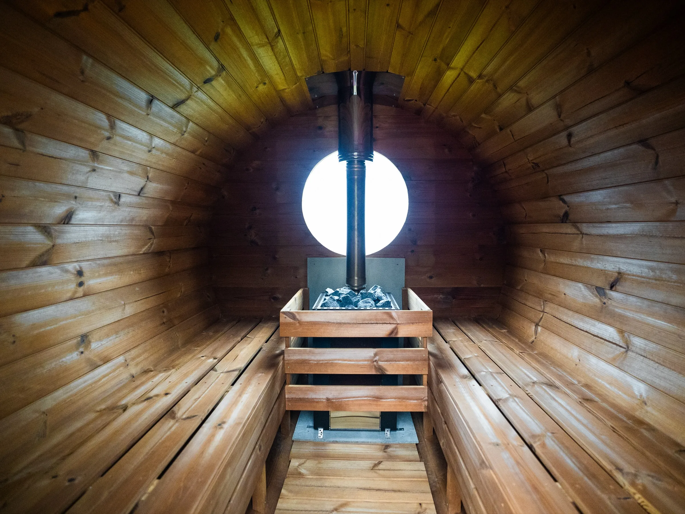 Inside the barrel sauna: wooden benches either side of the wood-burning stove
