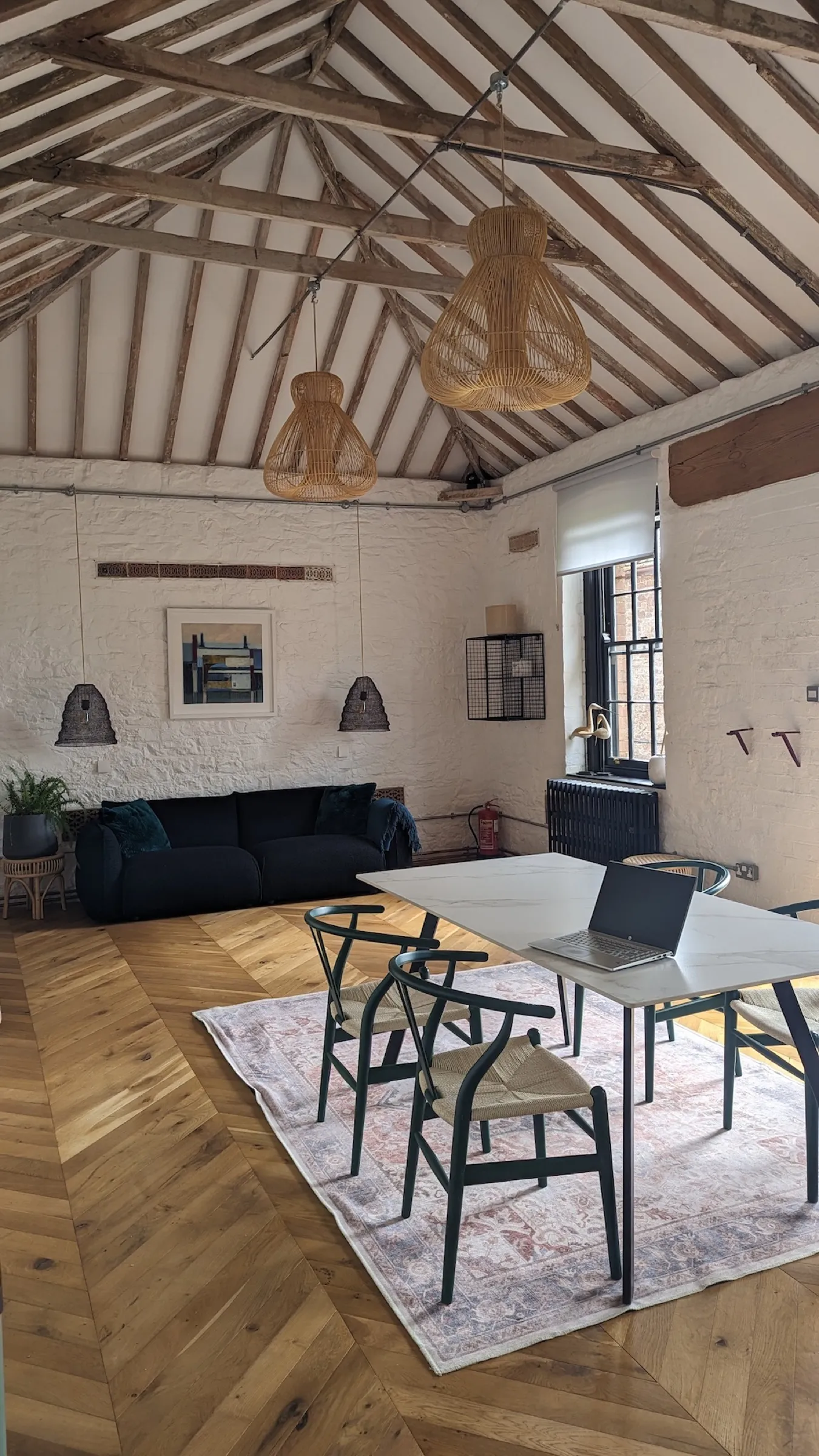 The Straw Store lounge with high beamed ceiling, sofa and work tables